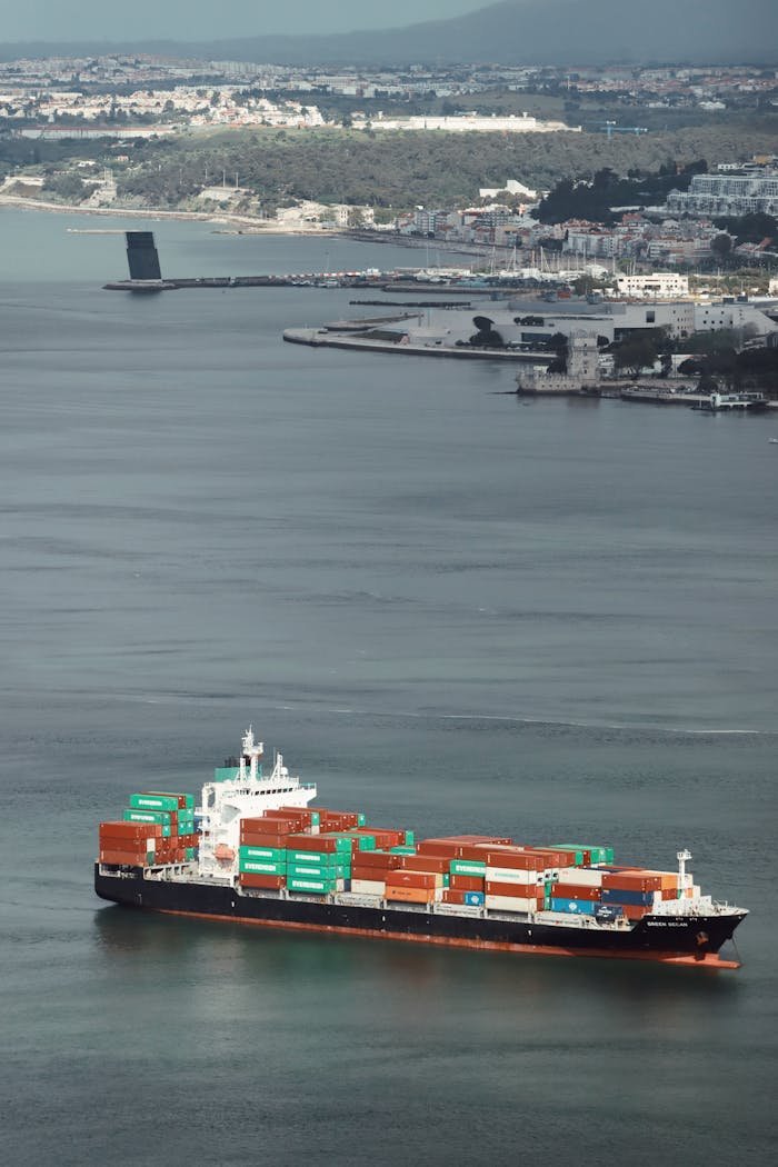 brand-01 Aerial view of a container ship navigating Lisbon Harbor, showcasing cargo transport.