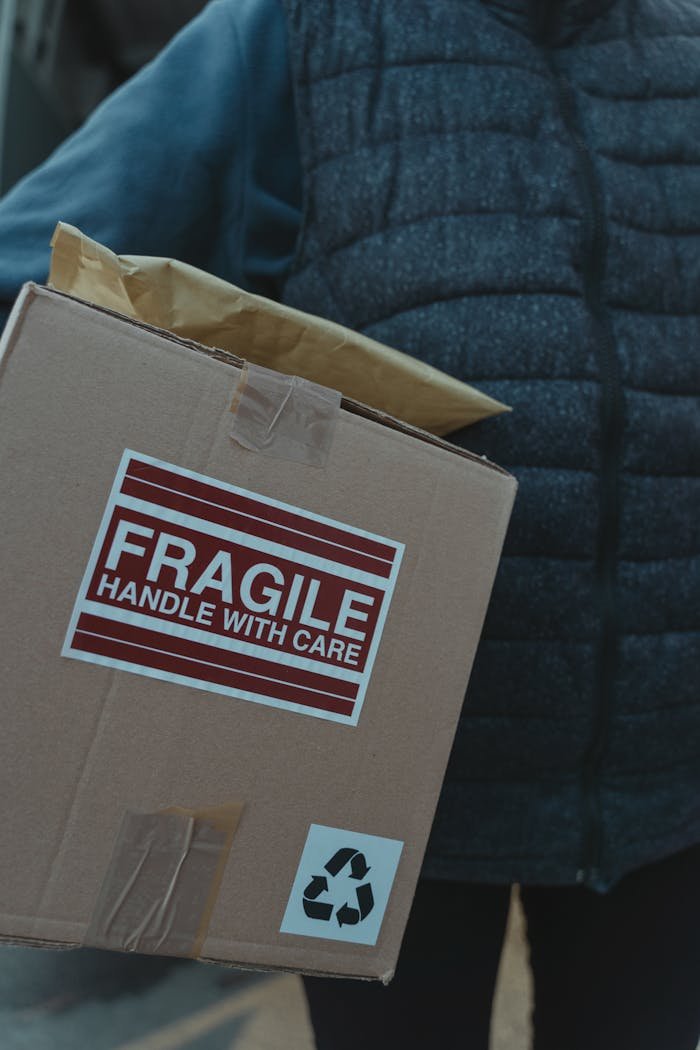 creative-02 Close-up of a fragile package with care labels being handled by a person.