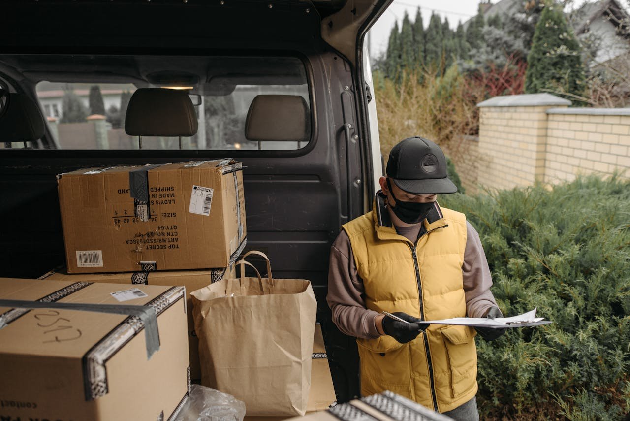 Services-03 Delivery worker checks documents among packages in a van.