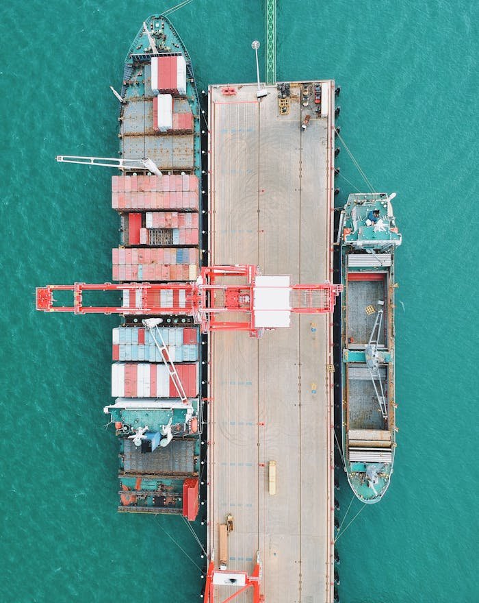 mobile-02 Aerial shot of cargo ships docked at a harbor with cranes and containers.